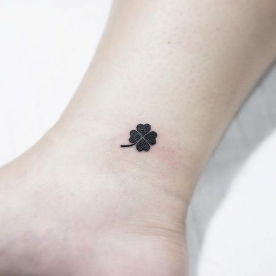 Tiny black clover tattoo on the inner ankle