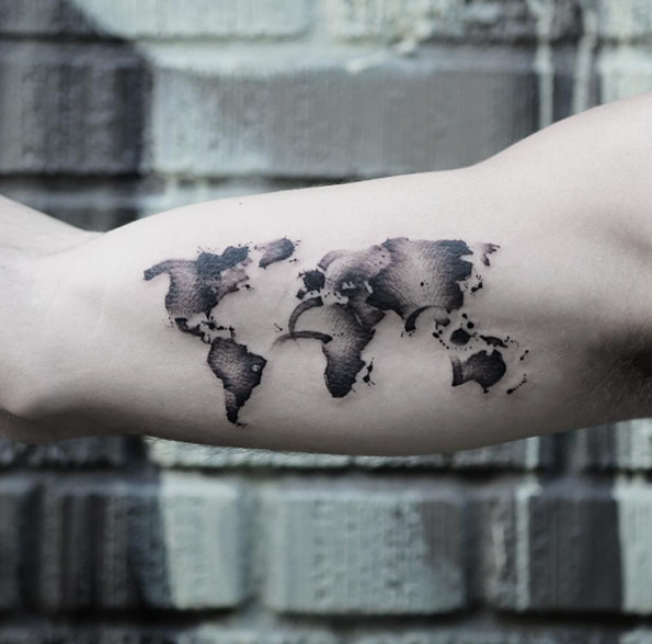 Black watercolor world map tattoo on the bicep