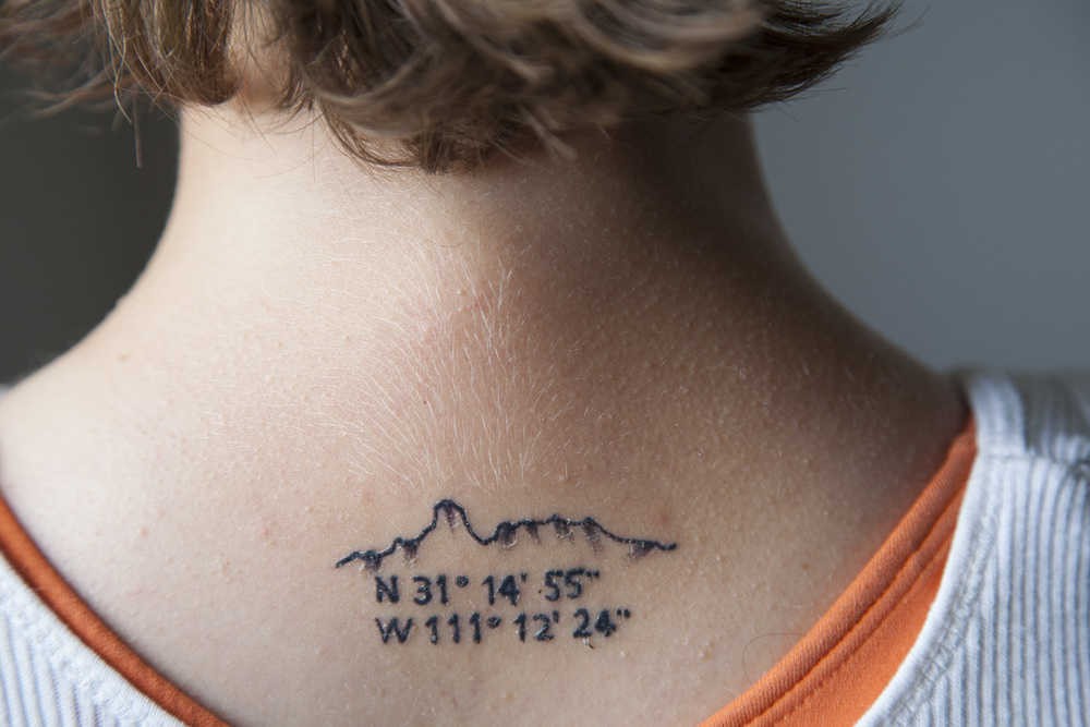 Coordinates and mountain tattoo on the upper back