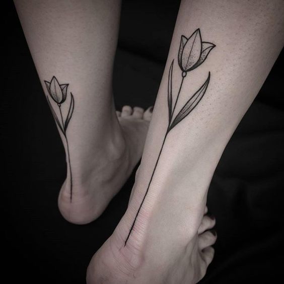 Matching black tulip tattoos on both calves
