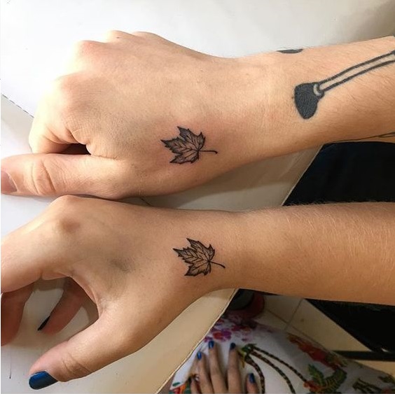 Matching maple leaf tattoos on hands
