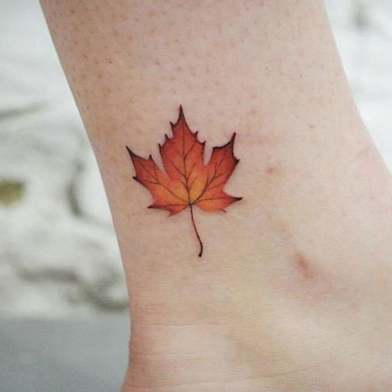 Orange maple leaf tattoo on the ankle