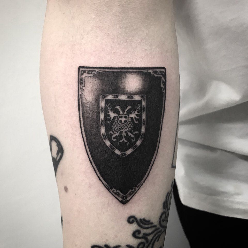 Blackwork shield tattoo on the forearm