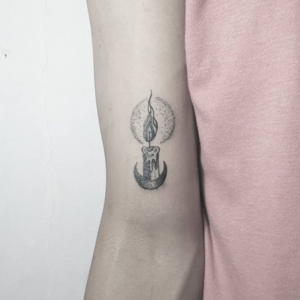 Small candle and crescent moon tattoo on the arm